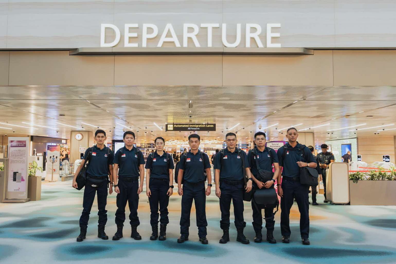 Seven uniformed personnel posing for a photo before departure.