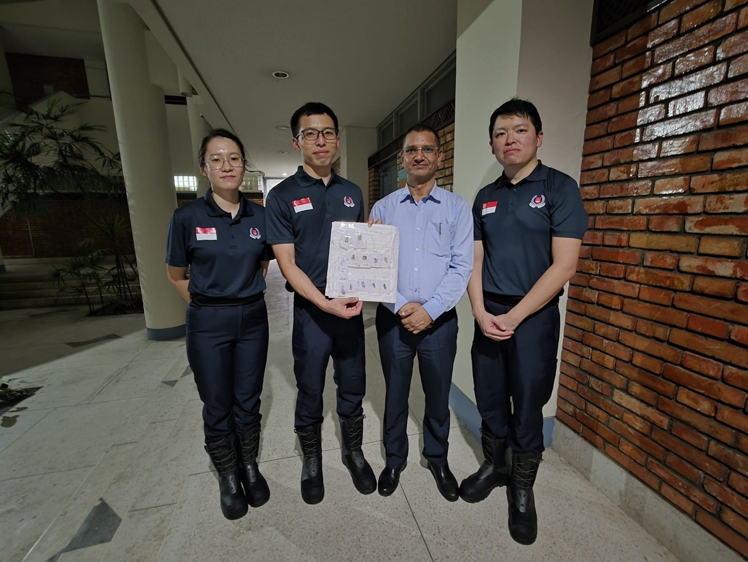 Four adults posing, with one holding a document.