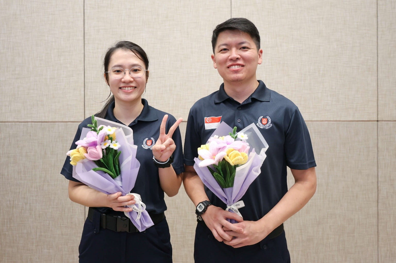 Two officers holding a flower bouquet each.