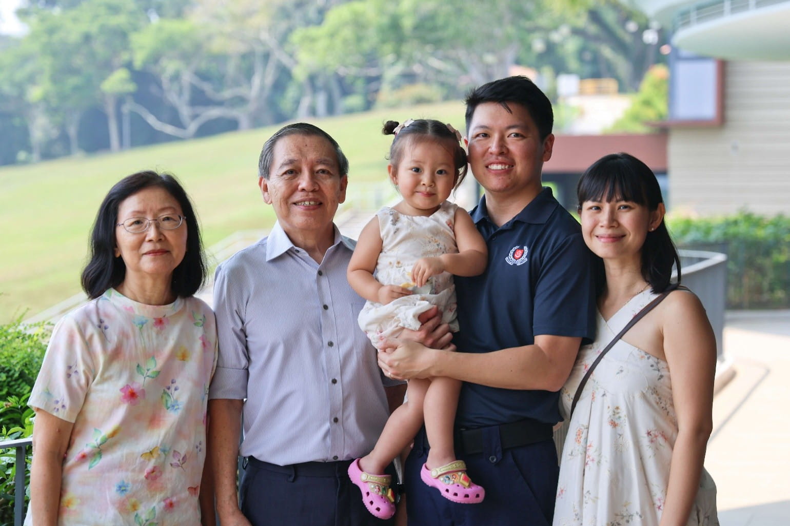Family portrait showing two elderly adults, two adults and a young girl outdoors.