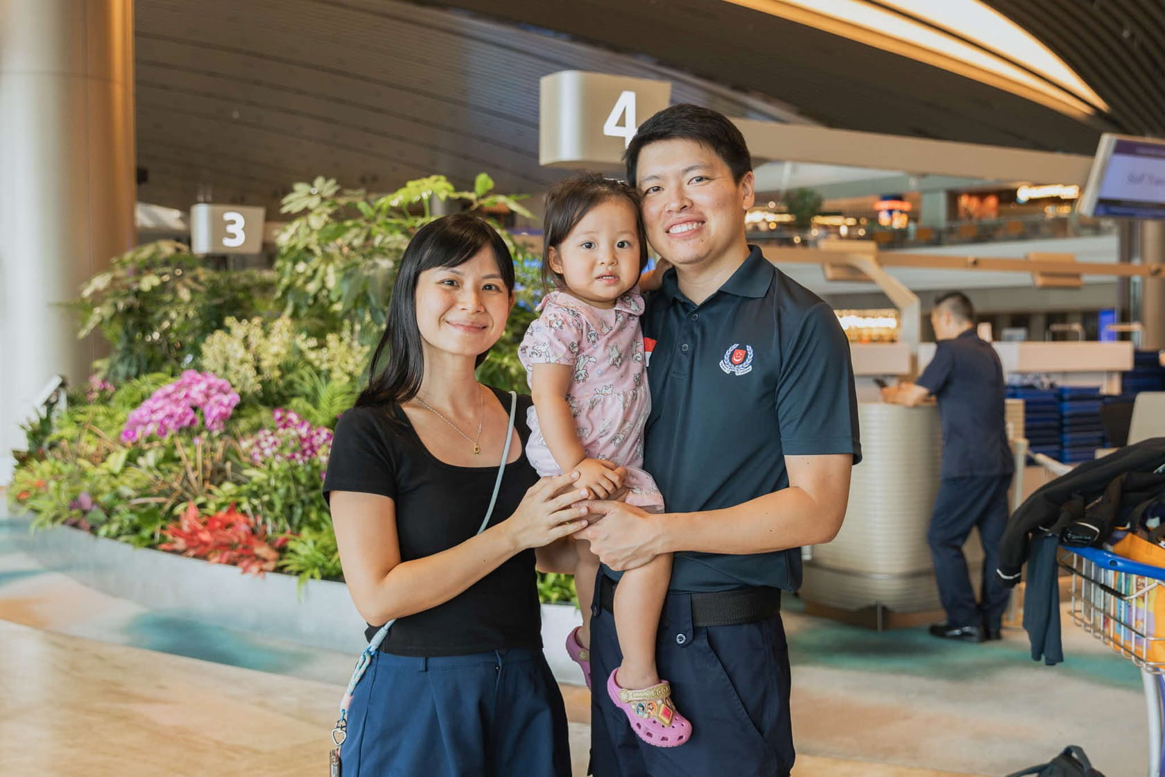 Family of 3 posing inside an airport terminal.