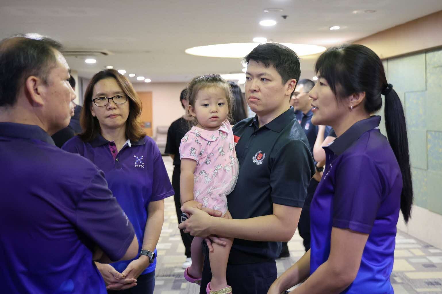 Adults speaking with a man holding a young girl.