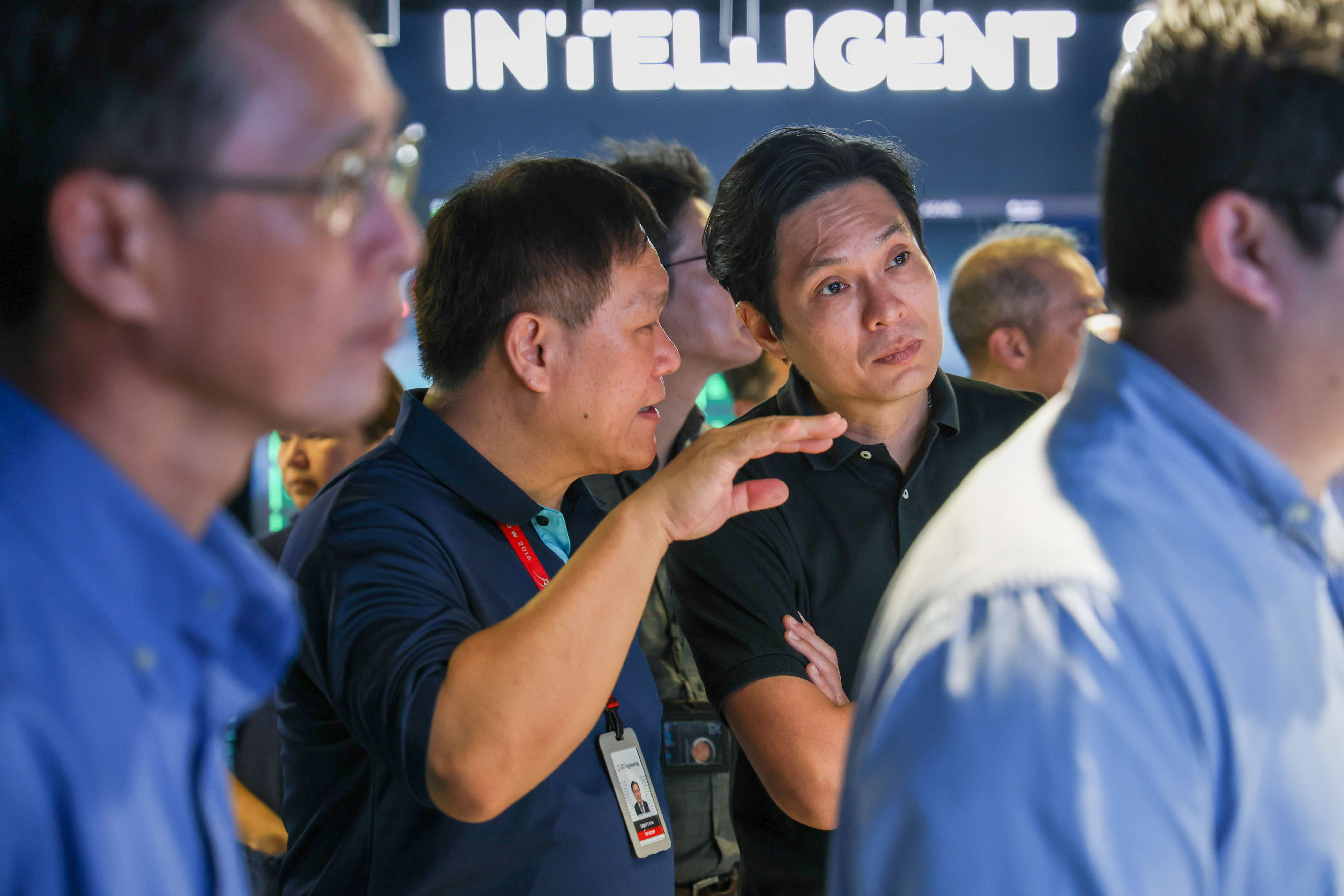 Two men engaged in a discussion, amidst a group of men.