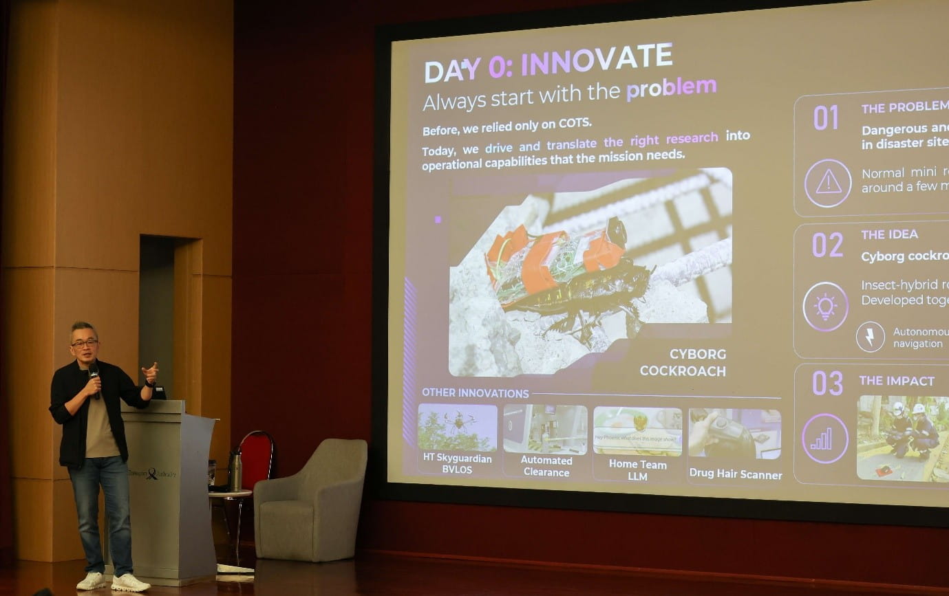 Presenter beside a projected innovation slide.