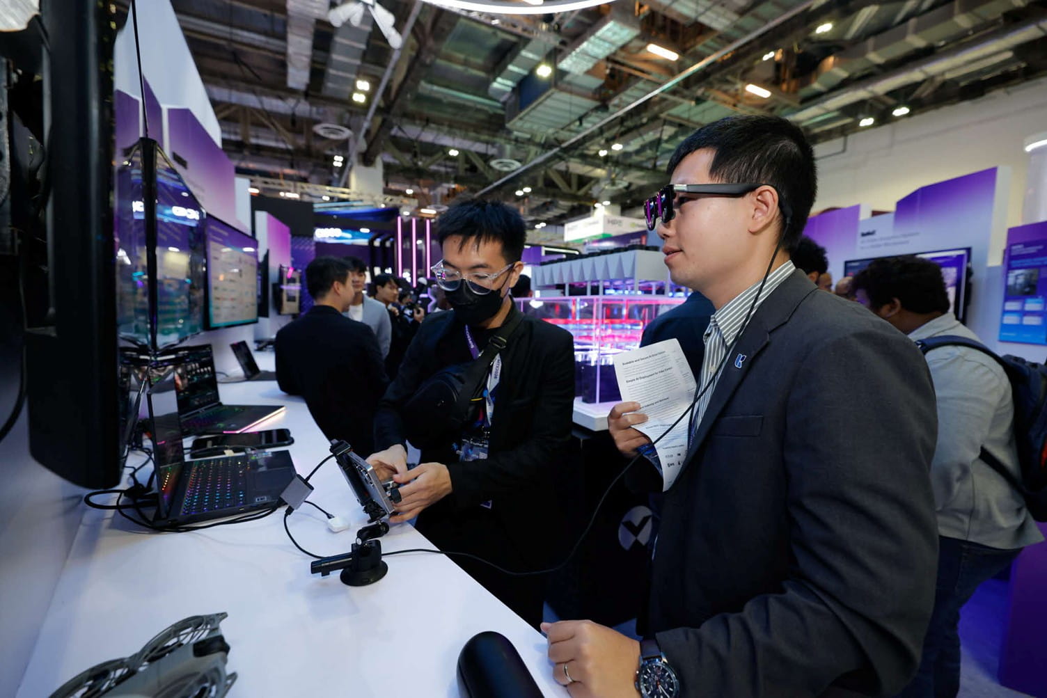 Two men interacting at a tech booth.