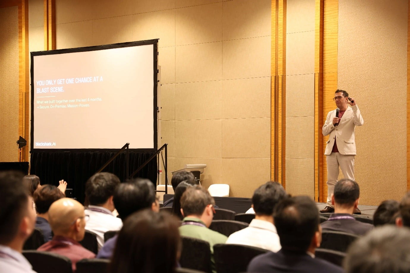 Man presenting on stage to a live audience.