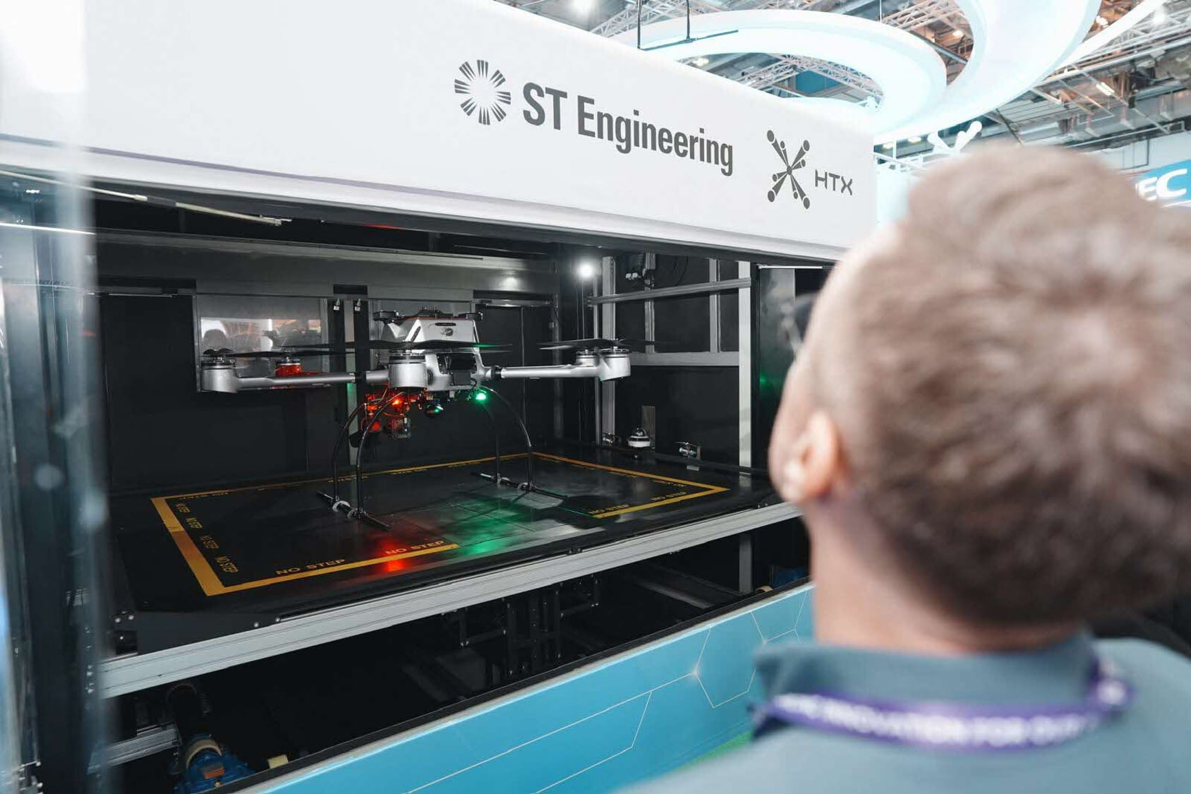 A person observing a drone inside a demo enclosure.