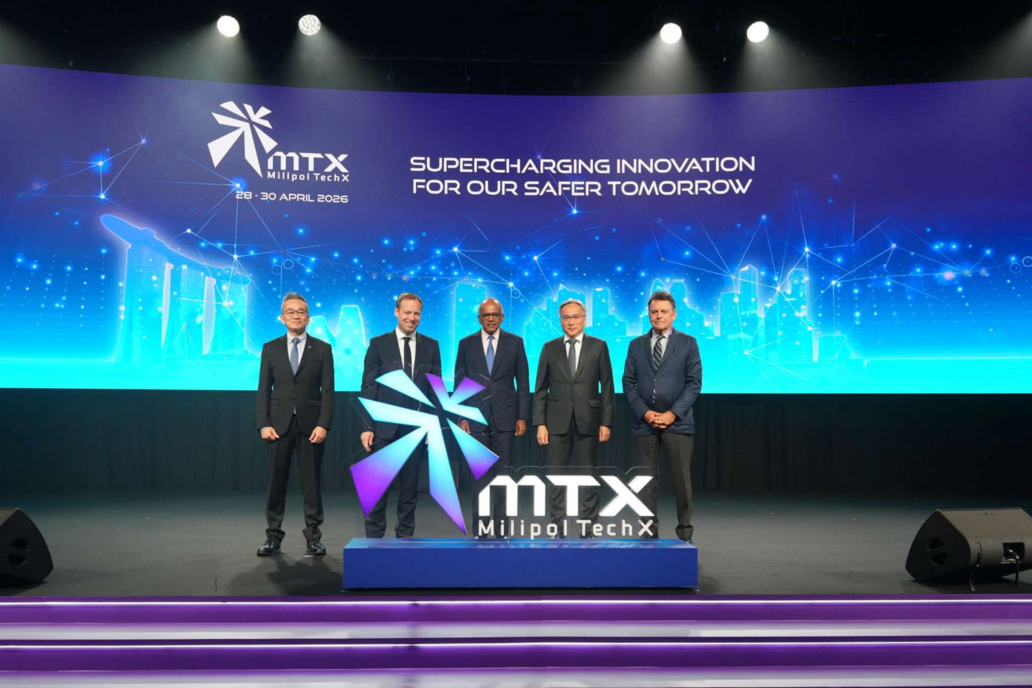 Five men in suits standing on stage.