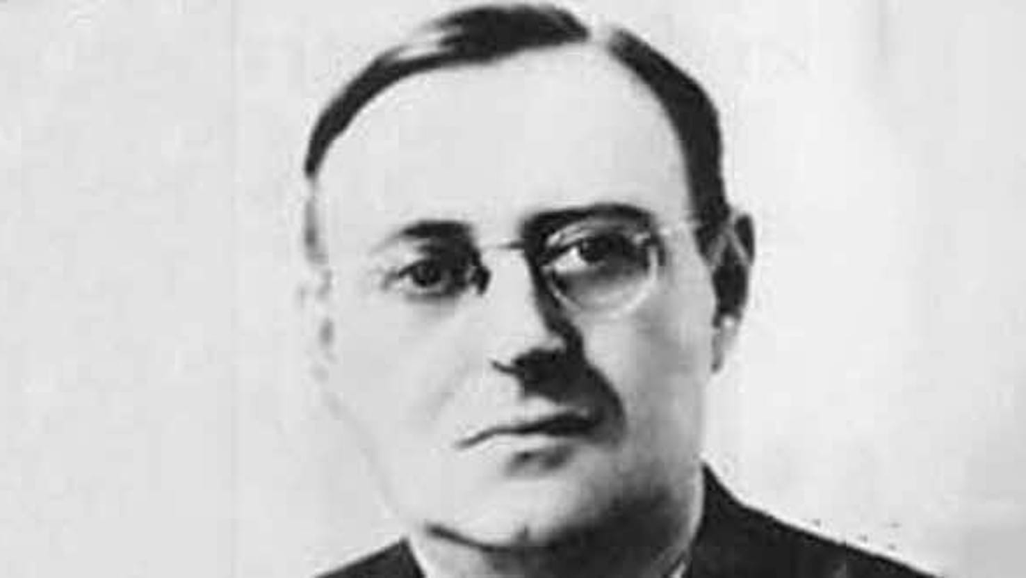 A black and white photo of a man, posed against a plain background.