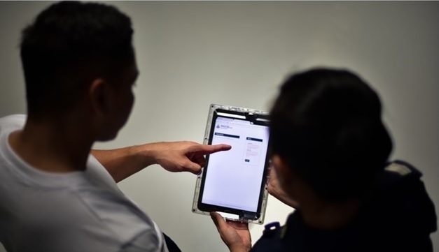 Two people viewing a digital form on a tablet, with one person pointing at the screen.