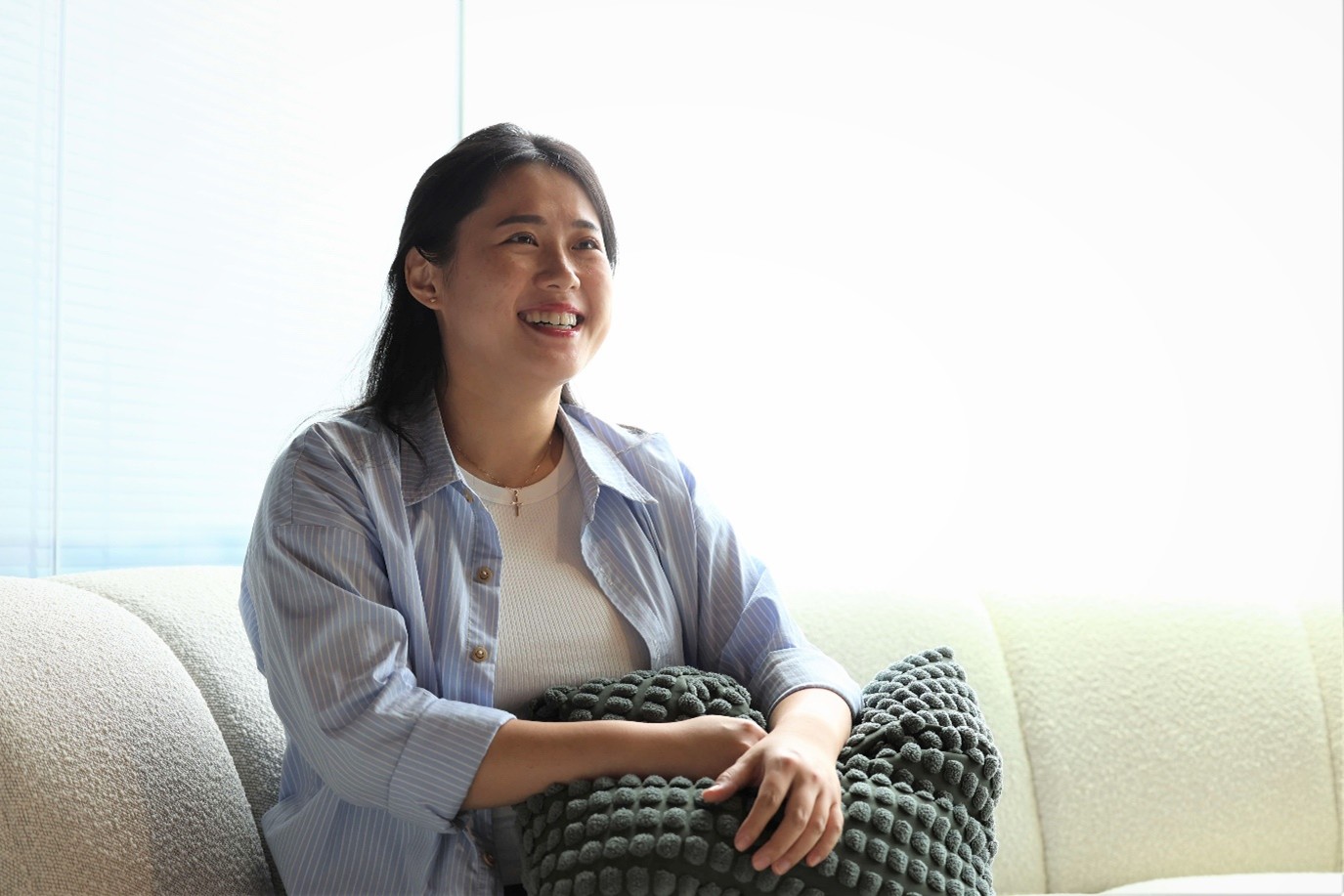 A female sits on a sofa holding a cushion.