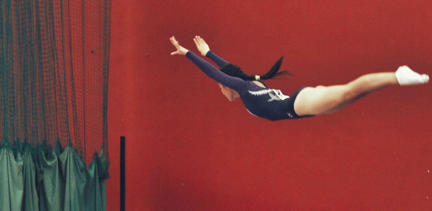 A woman in gymnastics outfit jumping in the air.