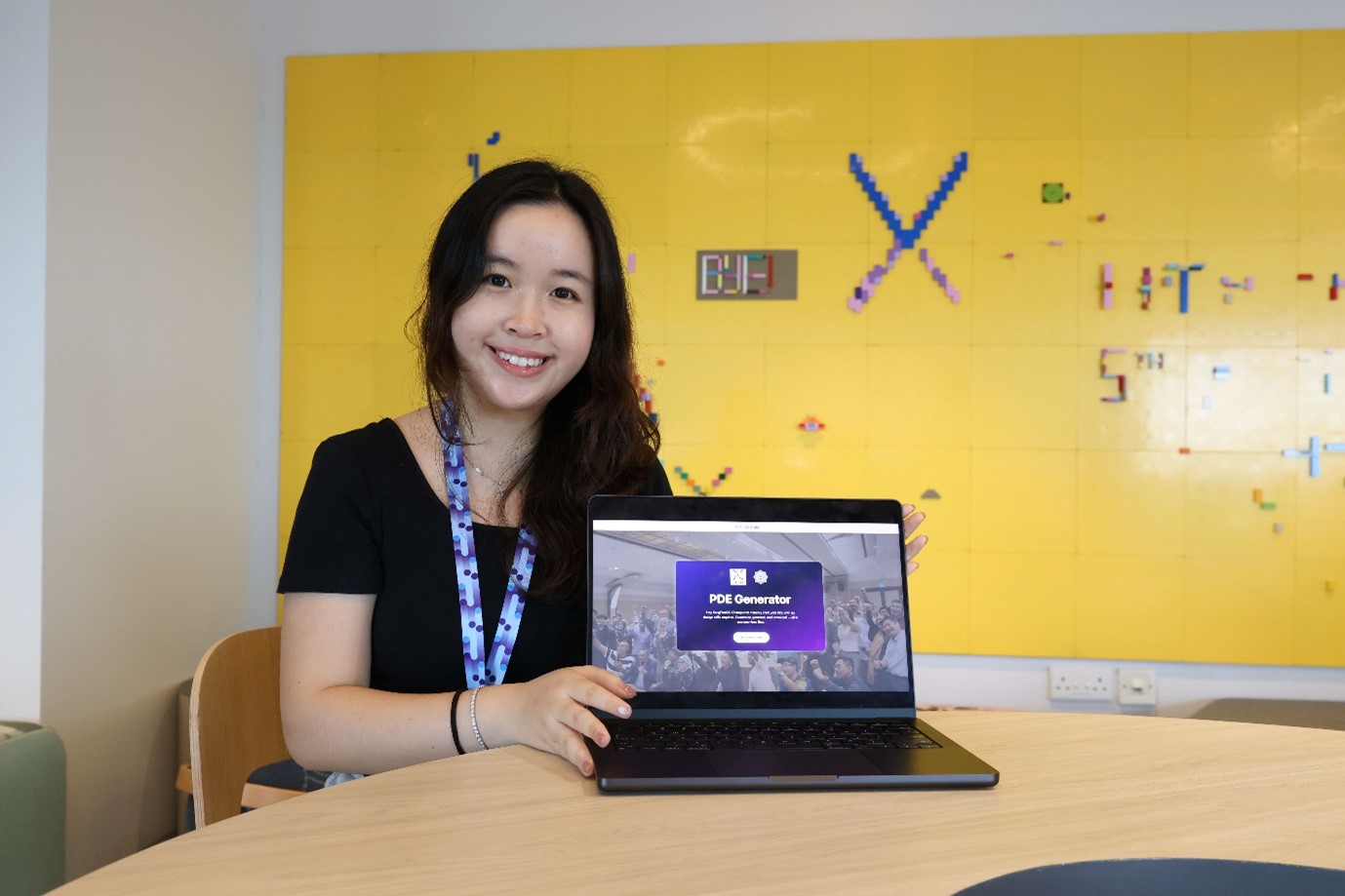 A young lady with a laptop screen displaying the words “PDE Generator”.