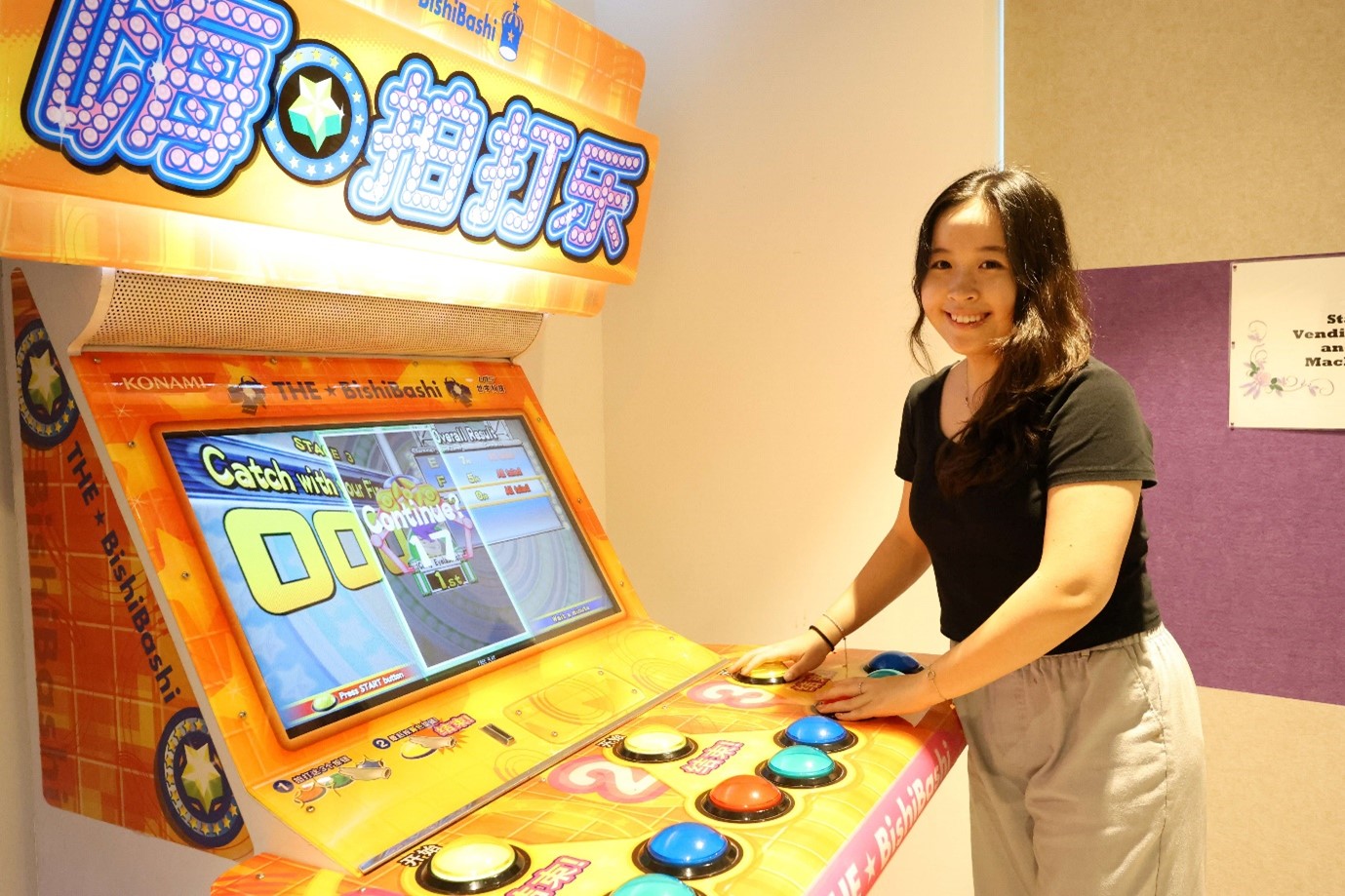 A young lady playing an arcade game machine with colourful buttons.