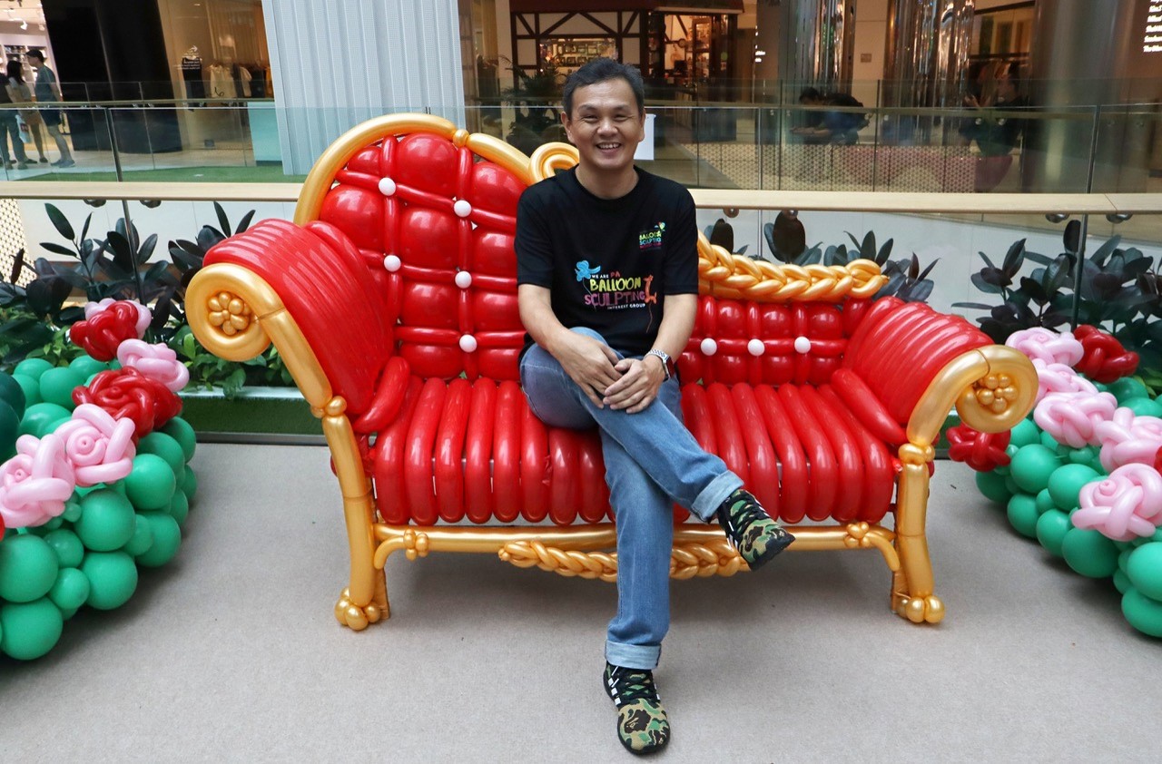 A man sitting on a chaise lounge made of balloons.