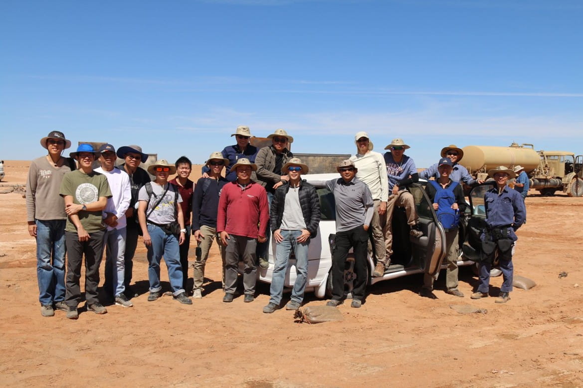 A group of people in a desert-like environment under a clear blue sky.