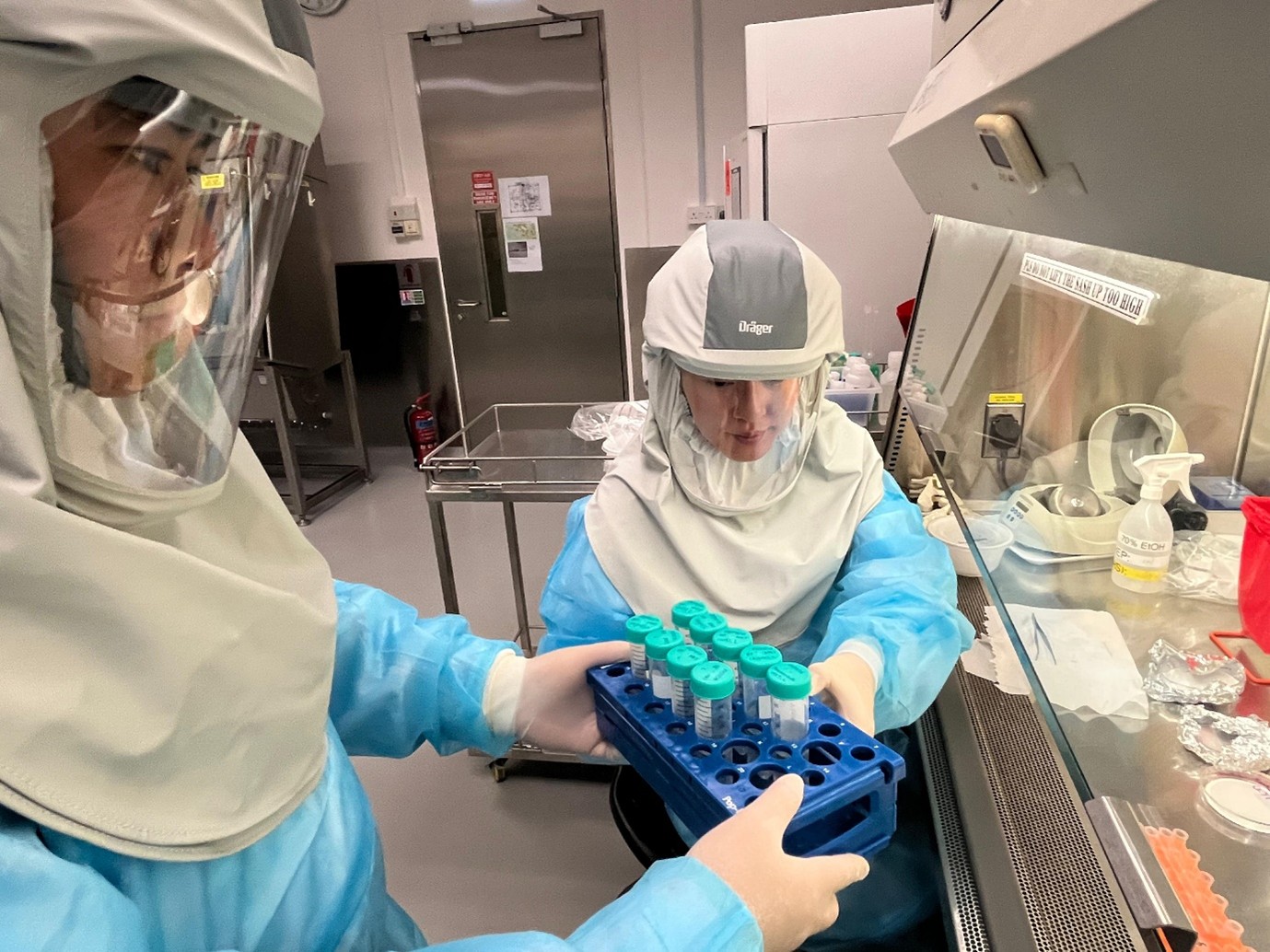 Two researchers in protective gear in a lab.