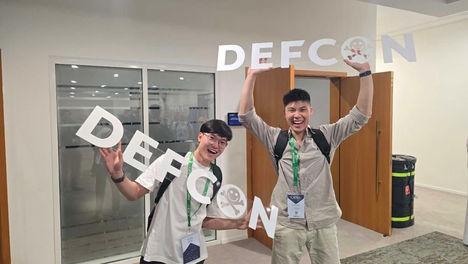 Two young men holding large letters spelling "DEFCON".