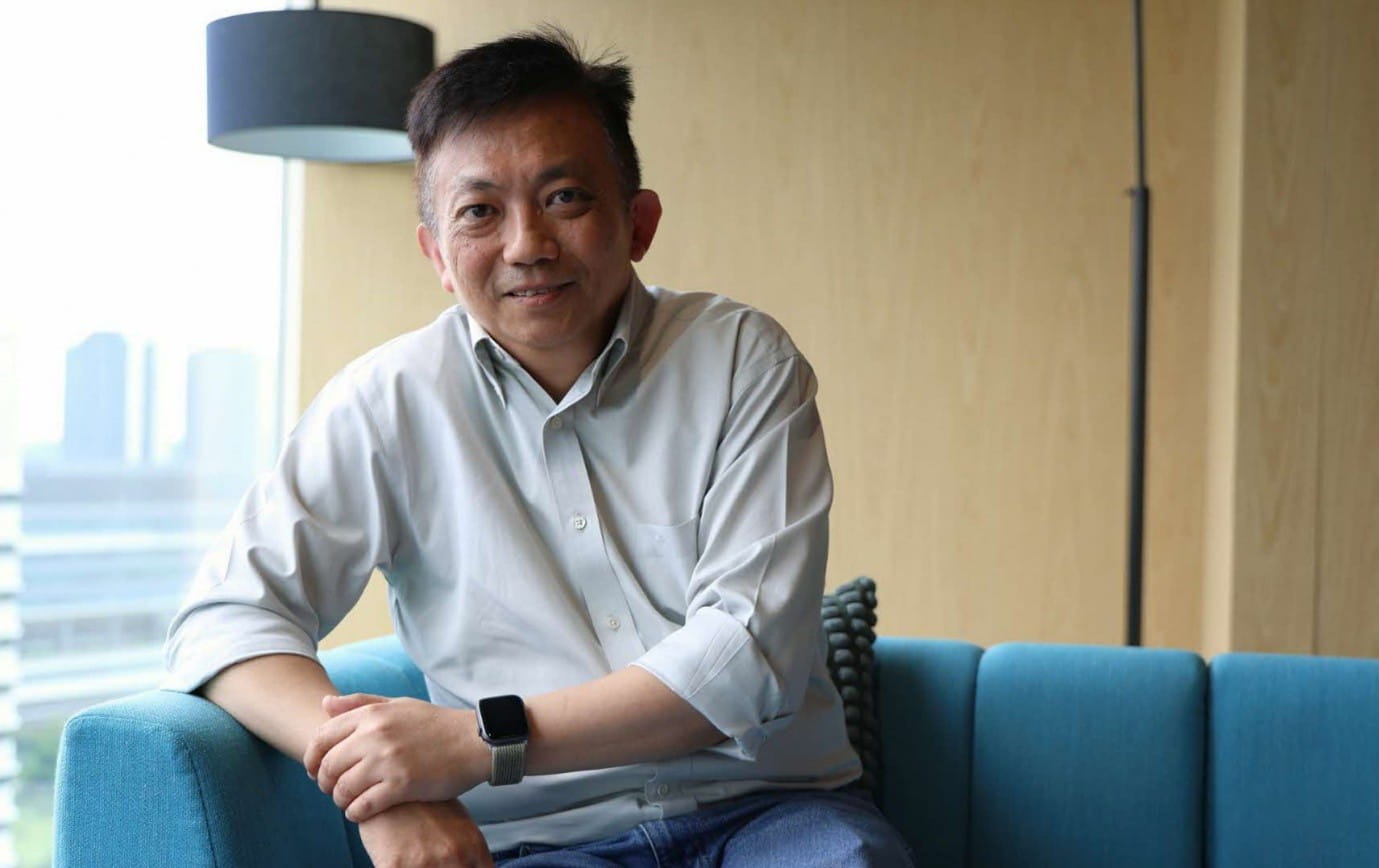 A man sitting on a blue couch in a modern indoor setting.