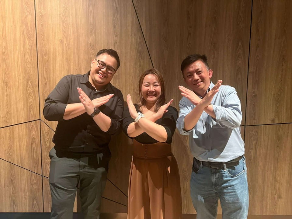 Three people making an "X" pose with their hands.