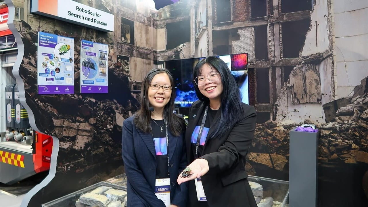 Two women pose in front of a "Robotics for Search and Rescue" exhibit.
