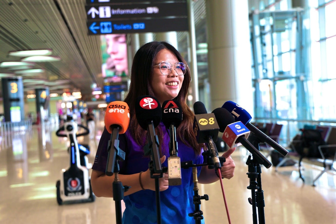 A woman speaking into news microphones.