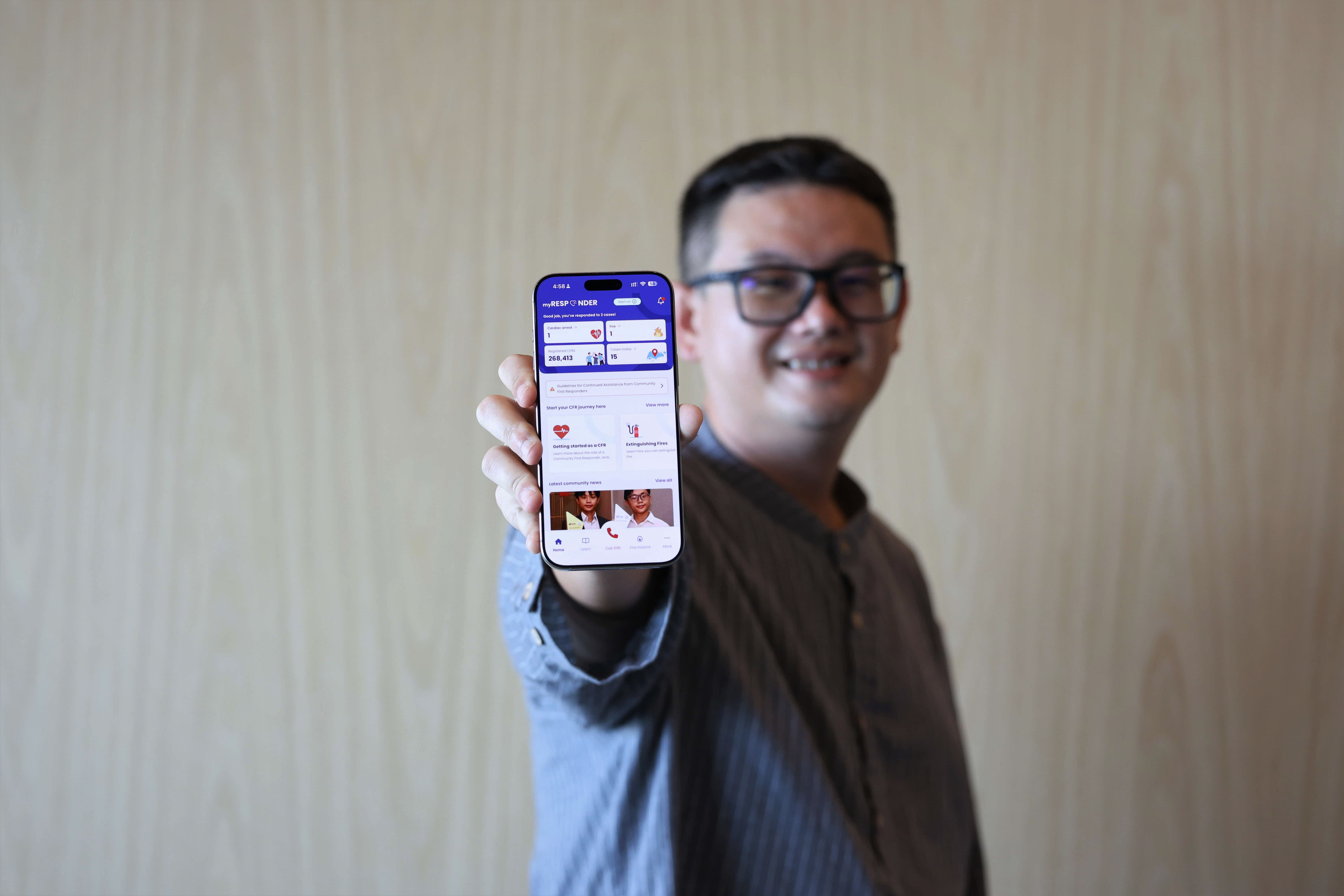 A man holds a smartphone displaying the mobile app interface, showing various icons, text, and images related to health or medical services.
