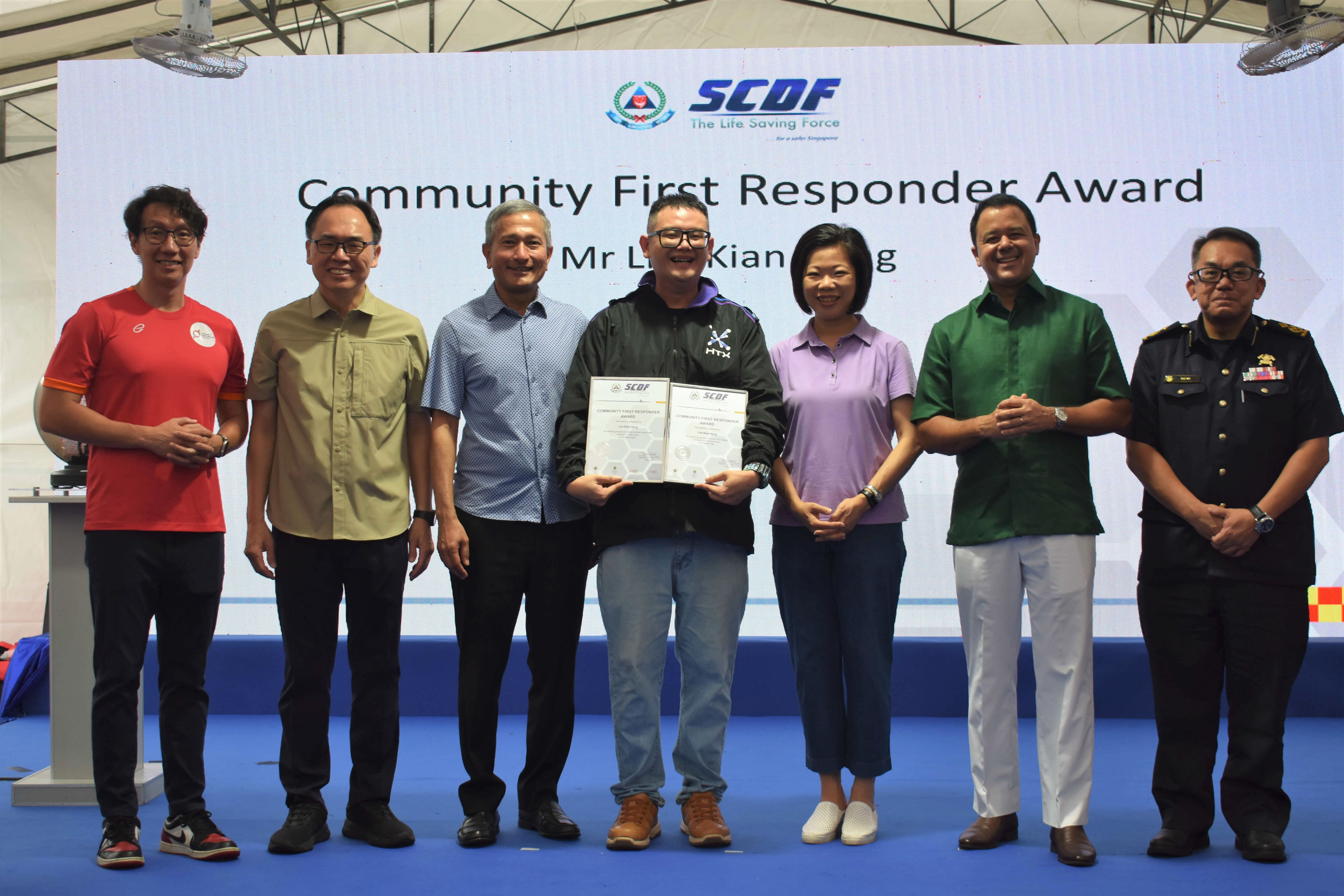 Seven people standing on stage during a Community First Responder Award ceremony, with one person holding a certificate.