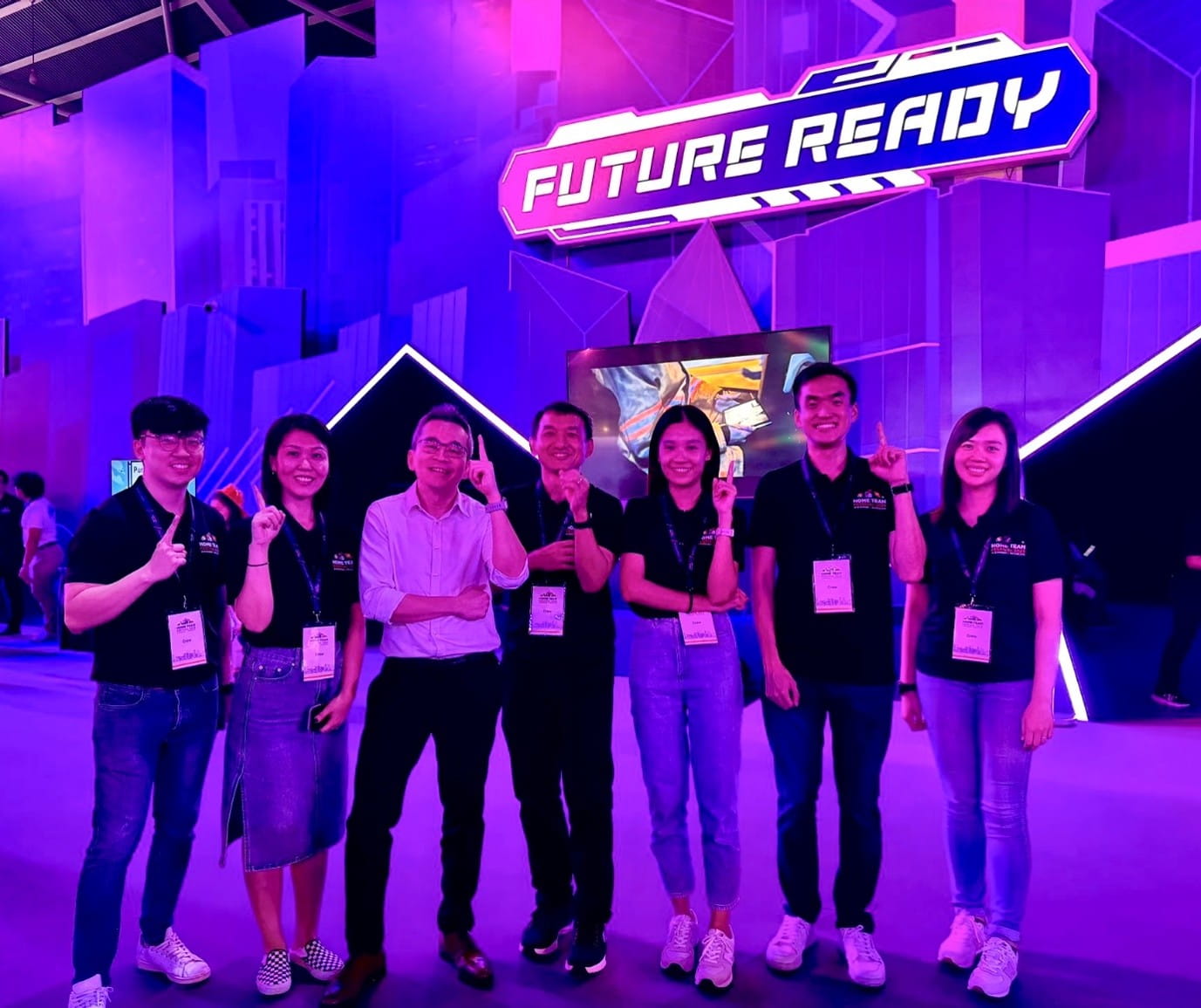 A group of people standing in front of a purple-lit backdrop with a large "Future Ready" sign above them.